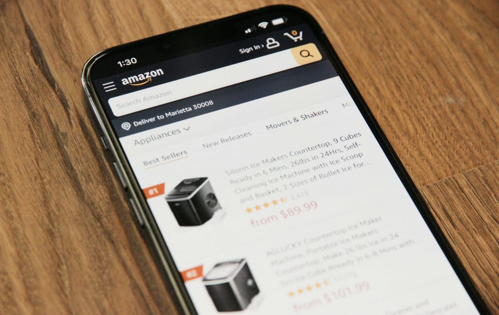 Amazon product listings on a mobile phone screen, resting on wood.