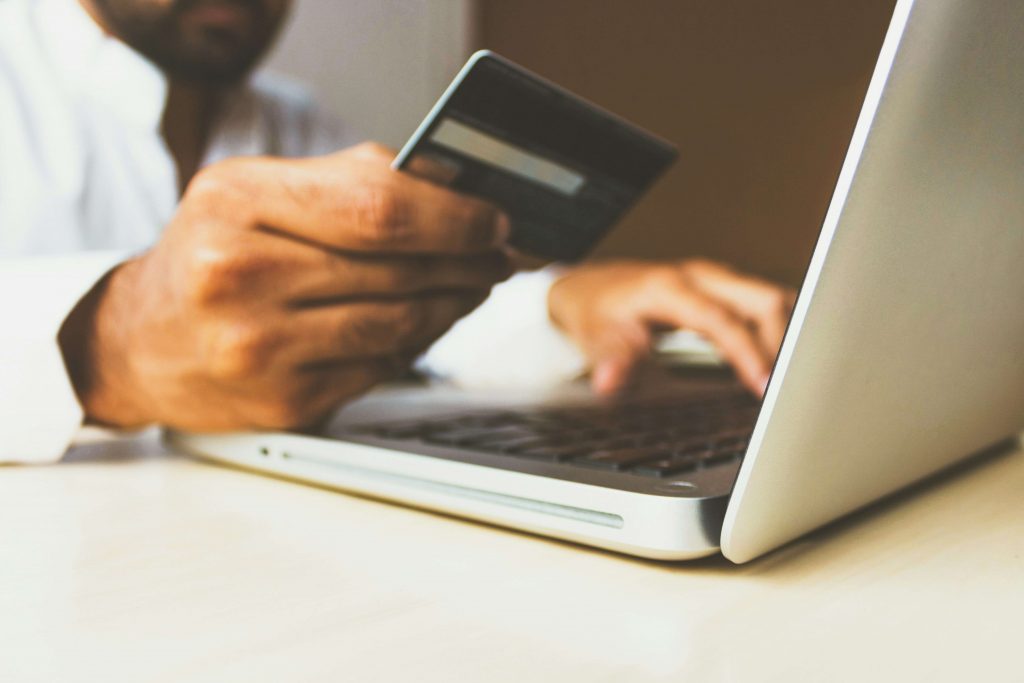 a person's hands typing on a laptop while holding a credit card.